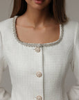 Abito in tweed bianco con polsini in piume